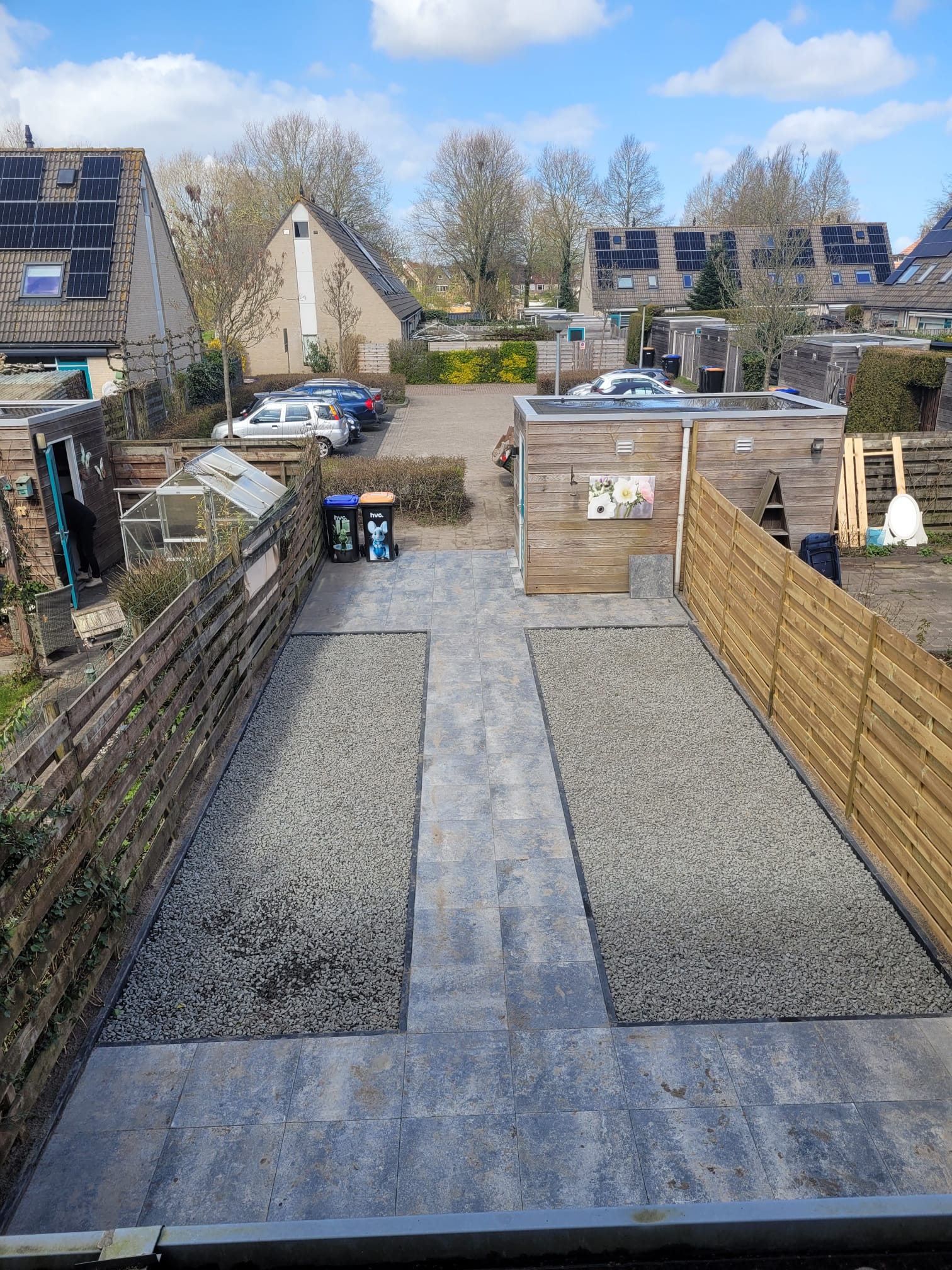 Nieuw tegelpad tussen twee grindstroken en houten schuttingen, van boven gezien